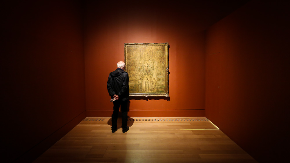 Man viewing a framed painting in a museum gallery